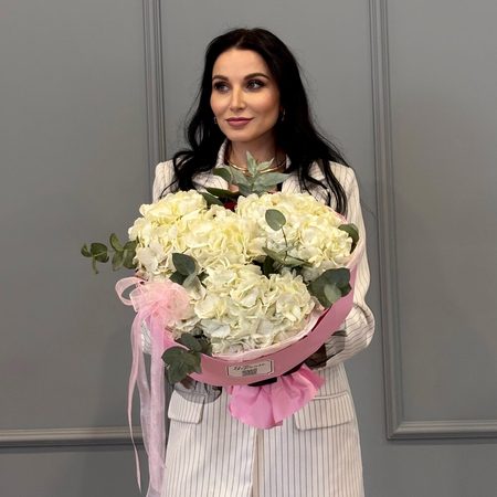 Три белых гортензий в круглой розовой упаковке
