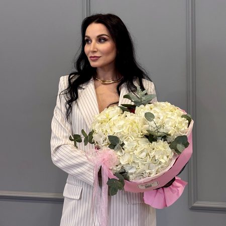 Три белых гортензий в круглой розовой упаковке
